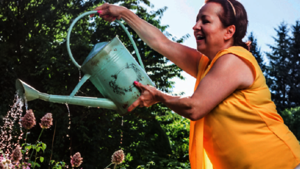 Vrouw geeft planten in de tuin water met een gieter